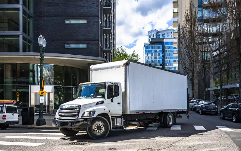 A box truck turns a corner in a downtown urban setting