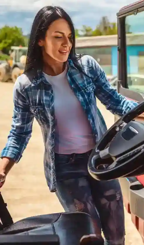 A woman getting into the drivers seat of a truck cab 