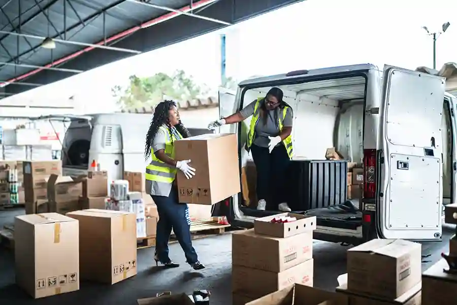 Two people unload boxes from a van